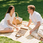 Couple playing chess on brown 3-in-1 travel game set during picnic, ideal for romantic and casual outdoor activities.