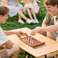 Group of friends playing checkers on brown 3-in-1 travel game set at outdoor picnic table, ideal for social gatherings.