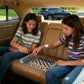 Two girls playing chess on a gray travel game set in a car, perfect for family travel and bonding.