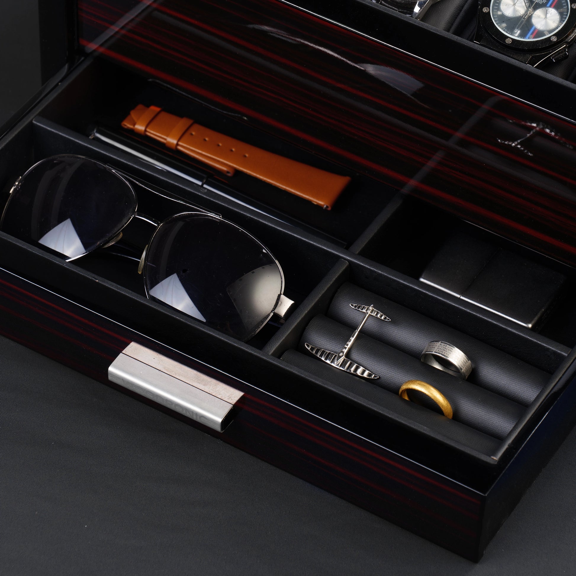 Close-up of watch box drawer with divided storage for sunglasses, watch straps, rings, and cufflinks, ideal for accessory organization.