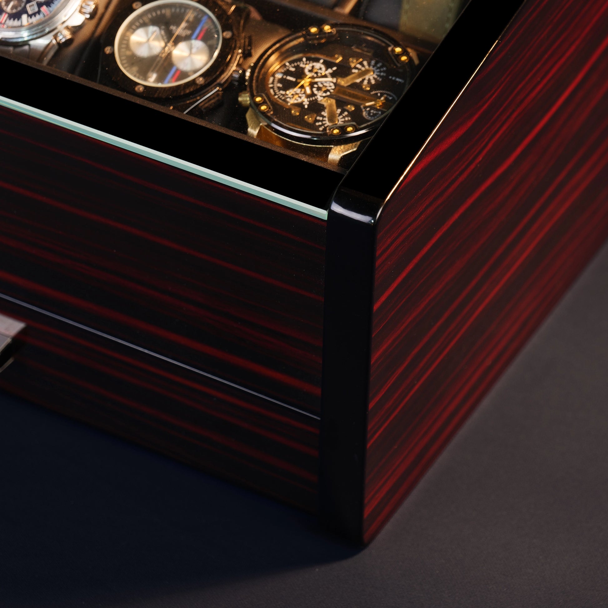 Close-up of ebony wood watch box with red grain and high-gloss finish, highlighting premium craftsmanship and luxury design.