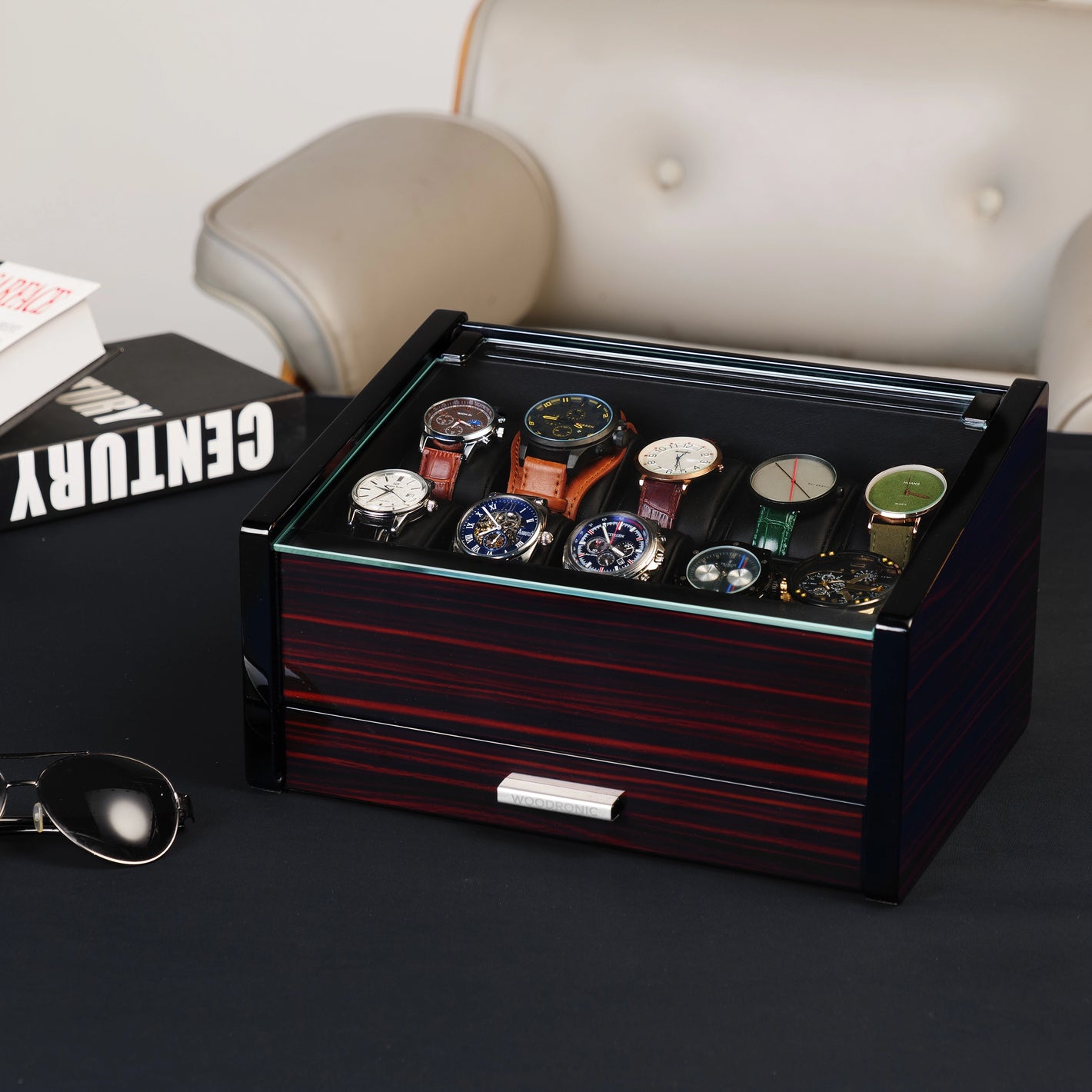 Ebony wood watch box with glass top displayed on a desk, showcasing luxury design and functional storage for watches and accessories.