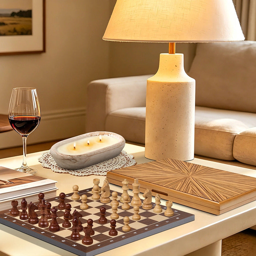 Wooden chess set with amber pearl pieces displayed on a minimalist coffee table, paired with a wine glass and candle for elegant leisure.
